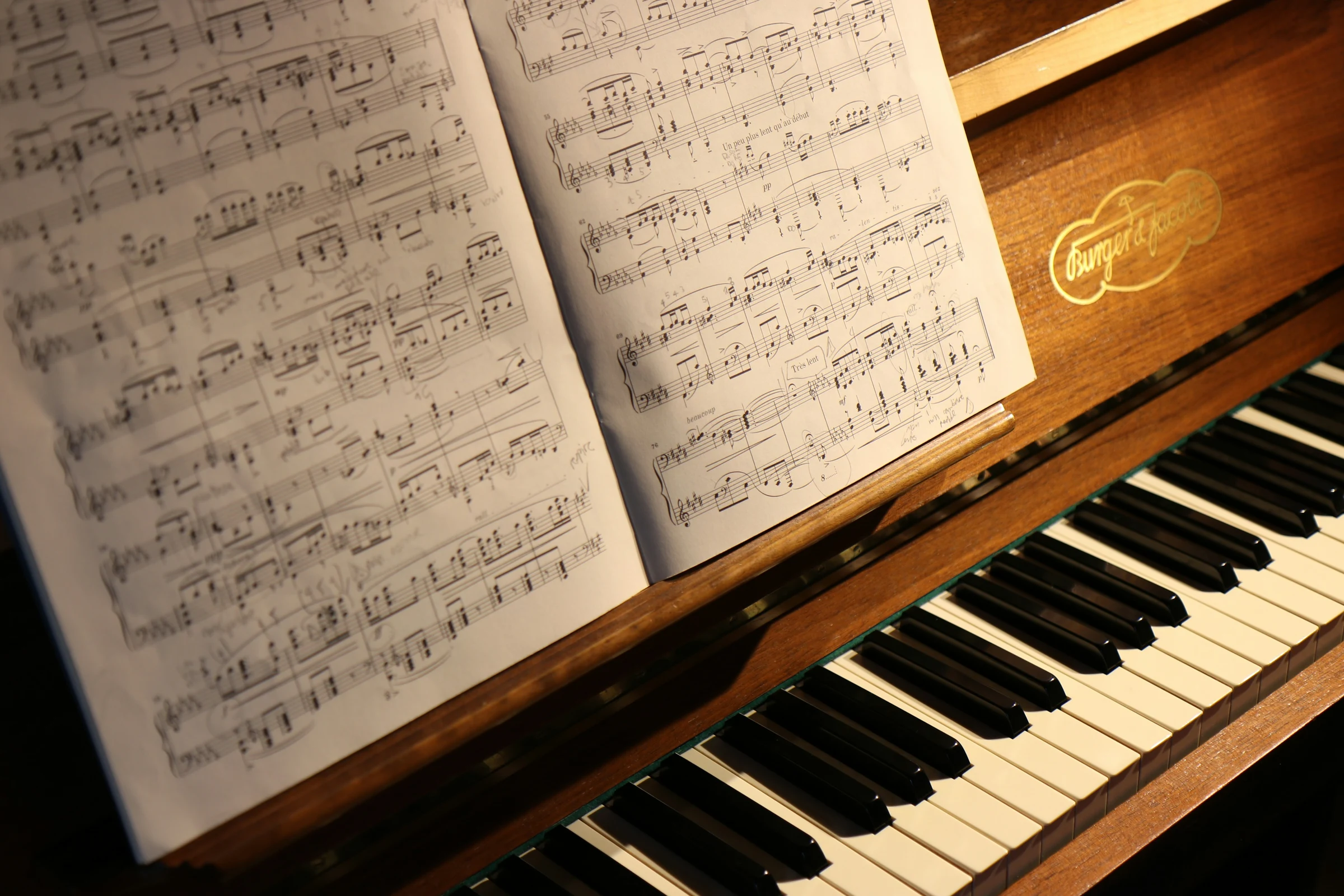 Sheet music resting on a warm brown upright piano in the church hall.